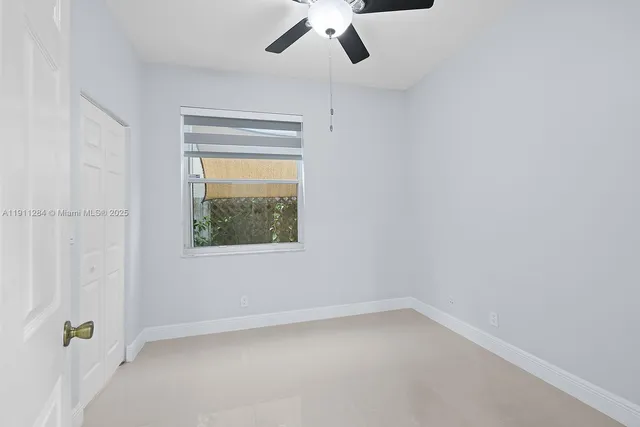 an empty room with a window and a ceiling fan