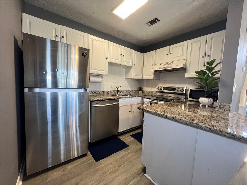 1496 Pine Log Road Northeast, Unit A Conyers, GA 30012 - Photo 19 of 24 a kitchen with stainless steel appliances granite countertop a refrigerator a sink a stove a microwave and island