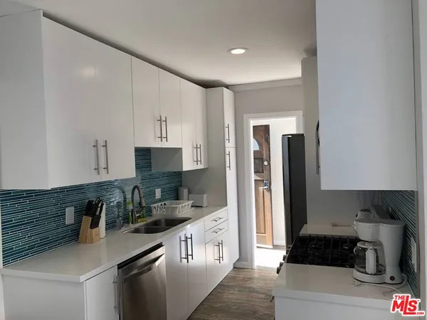 a kitchen with granite countertop a refrigerator a stove a sink a counter space and cabinets