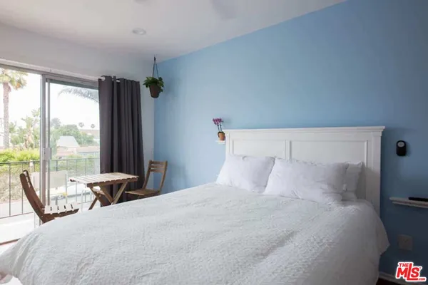 a bedroom with a large bed and large windows