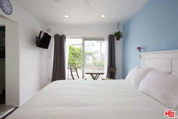 a bedroom with a large bed and a flat tv screen on dresser