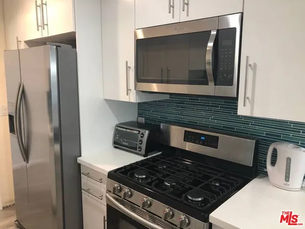 a kitchen with stainless steel appliances granite countertop a refrigerator and a stove