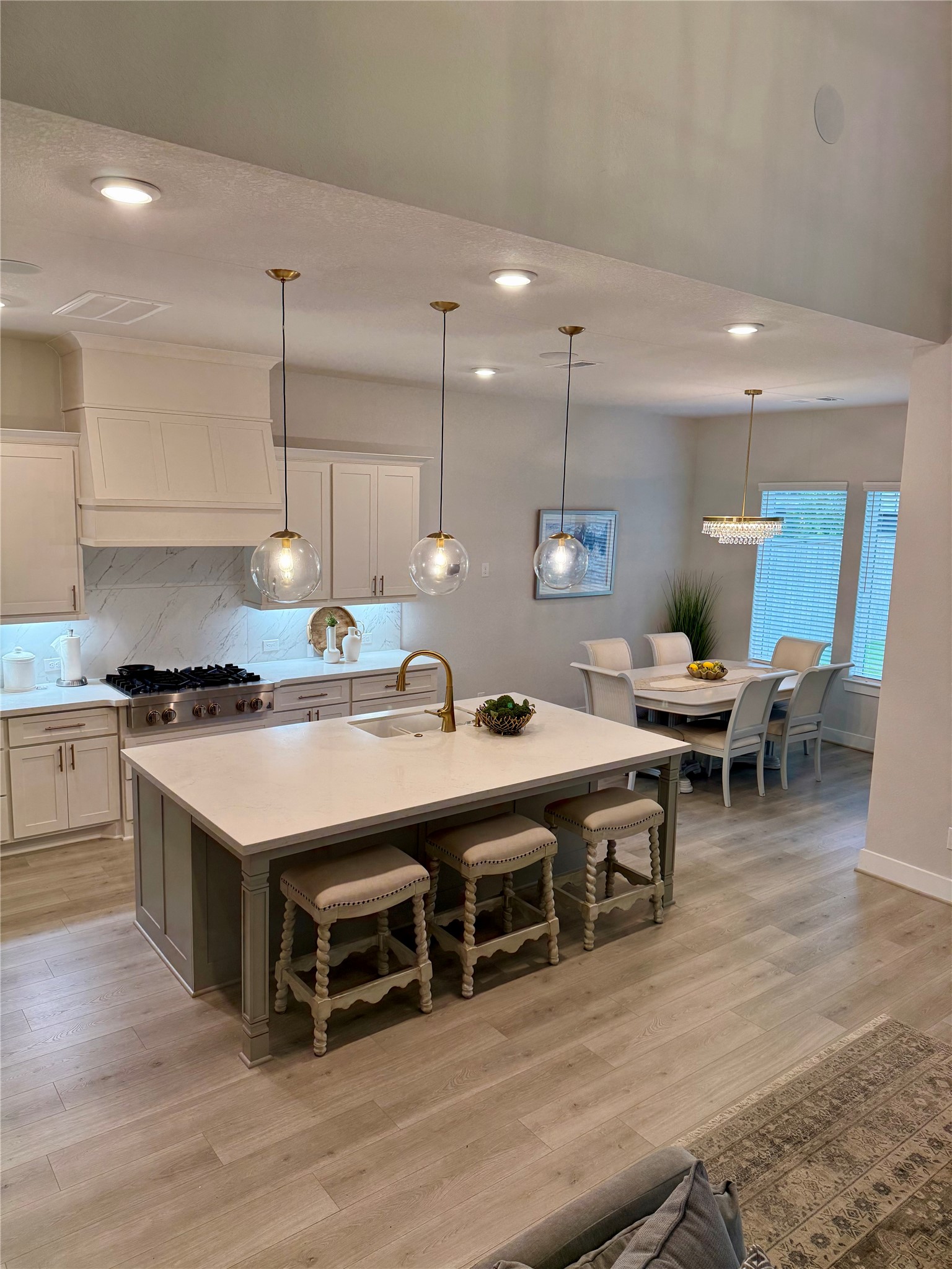 26923 Arethusa Court Spring, TX 77389 - Photo 27 of 44 This kitchen features a sleek, modern design with white cabinetry, stainless steel appliances, and a gas cooktop. The light backsplash and countertops add a touch of elegance, while the light wood flooring complements the bright, airy feel.
