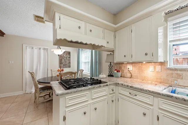 a kitchen with stainless steel appliances a sink a stove and white cabinets
