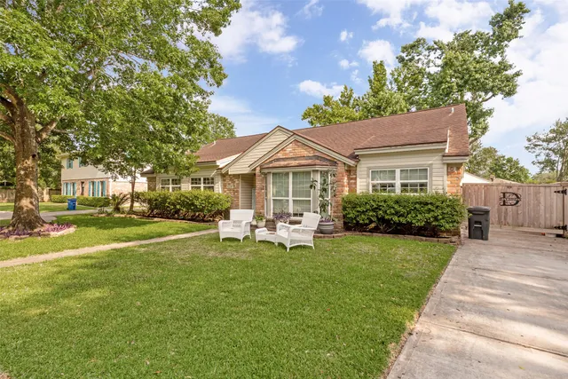 a front view of a house with garden and trees