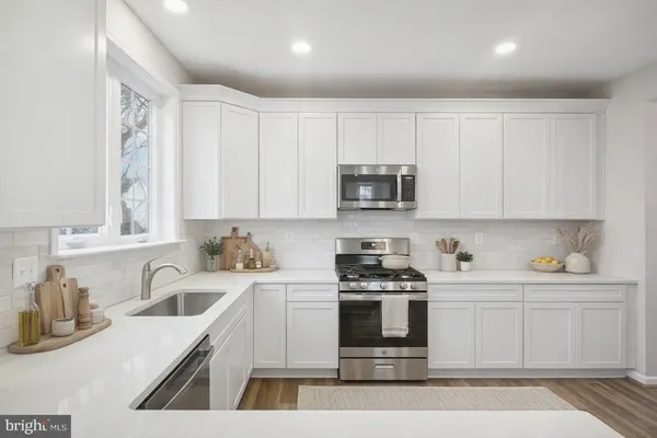 a kitchen with stainless steel appliances granite countertop a sink a stove a microwave a counter space and cabinets