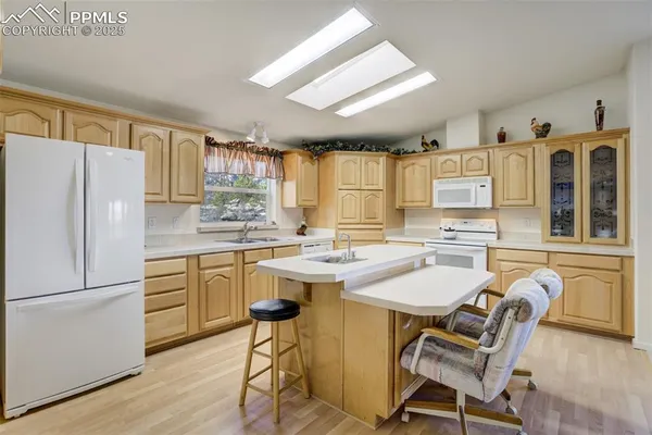 a kitchen with a refrigerator a stove a sink and white cabinets with wooden floor