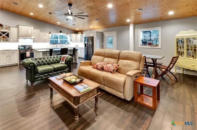 a living room with furniture kitchen view and a wooden floor