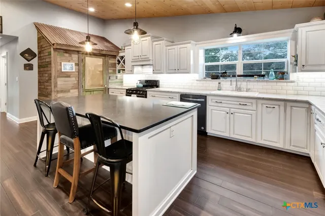 a kitchen with stainless steel appliances kitchen island a table chairs in it and wooden floors