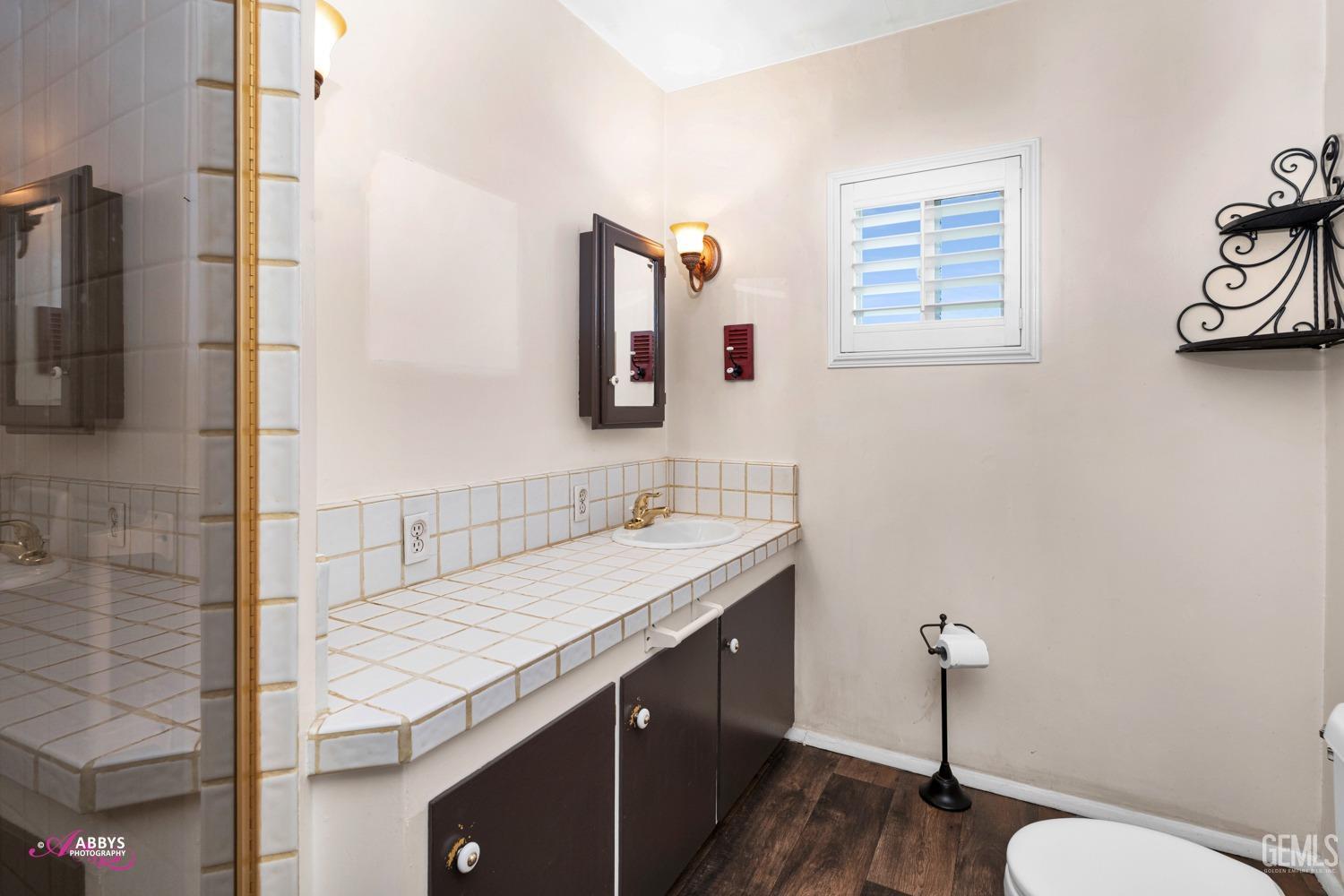 Undisclosed Address Bakersfield, CA 93309 - Photo 21 of 33 a bathroom with a granite countertop sink a toilet a mirror and shower