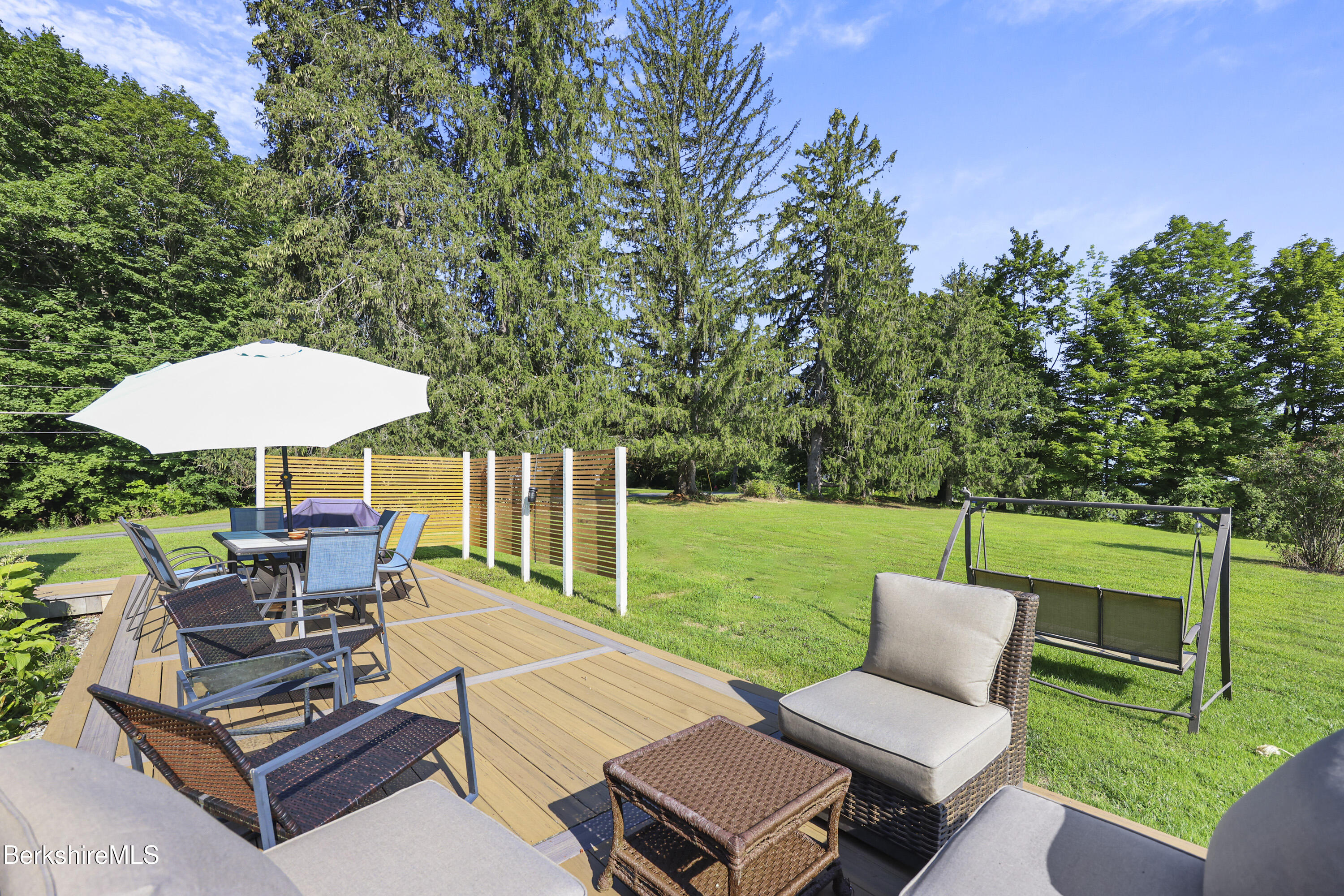 9 Castle Hill Road Stockbridge, MA 01262 - Photo 42 of 47 a view of a patio with couches table and chairs under an umbrella with large trees and big yard