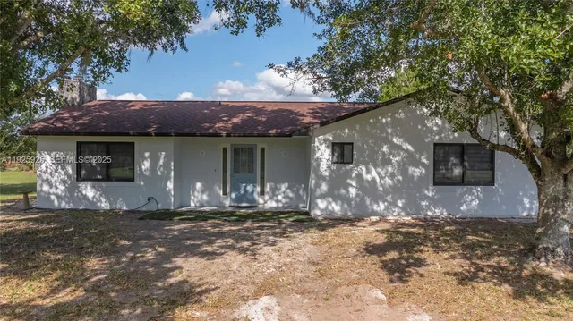 a front view of a house with a yard and tree s