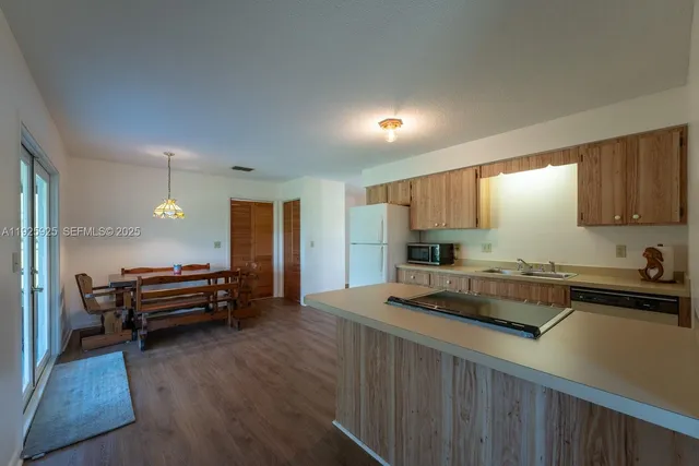 a view of kitchen with sink refrigerator and wooden cabinets
