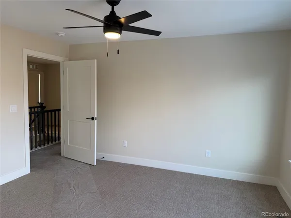 an empty room with a ceiling fan and carpet