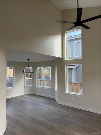 an empty room with wooden floor cabinet and windows
