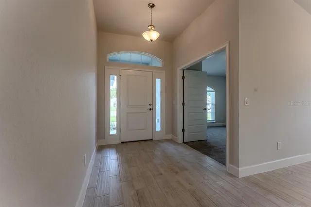 a view of a hallway with wooden floor and a chandelier