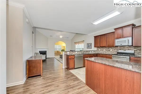 a kitchen with stainless steel appliances granite countertop wooden cabinets a sink a stove a dining table and chairs