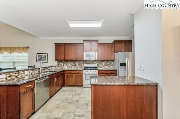 a kitchen with stainless steel appliances granite countertop a stove sink and cabinets