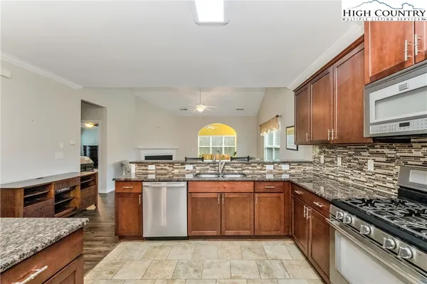 a kitchen with stainless steel appliances granite countertop a stove top oven a sink dishwasher a dining table and chairs