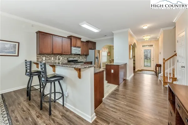 a view of a kitchen with kitchen island granite countertop wooden floors and a view of living room