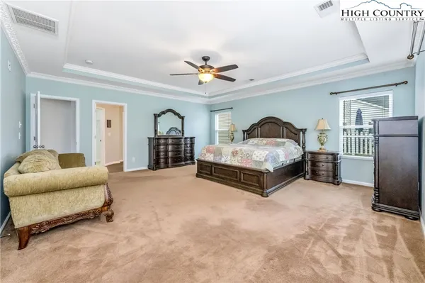 a spacious bedroom with a bed a couch and a chandelier
