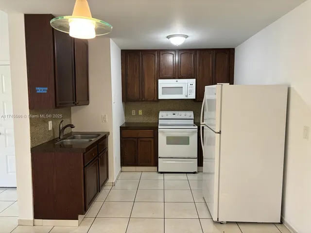 a kitchen with a refrigerator sink and cabinets