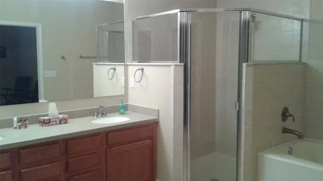 a bathroom with a shower sink vanity and mirror