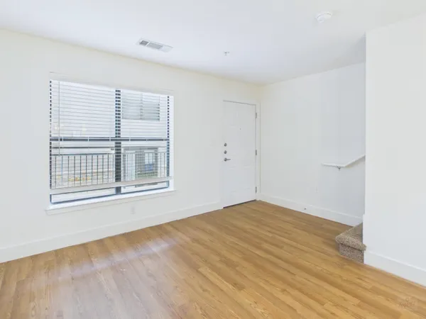 a view of an empty room with wooden floor and a window