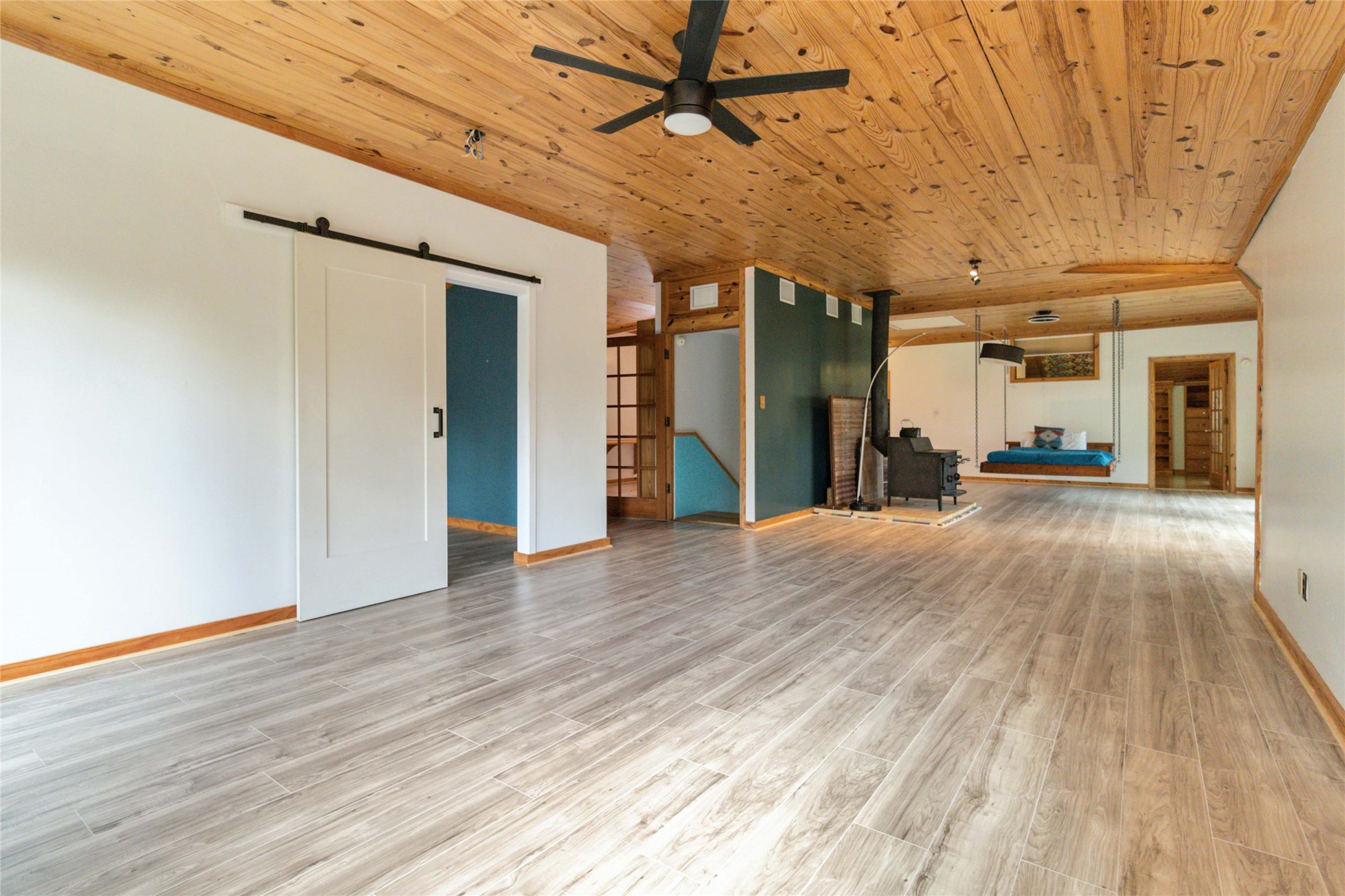 180 Ironstone Road Smithville, TX 78957 - Photo 15 of 37 Unfurnished living room featuring a barn door, ceiling fan, wood ceiling, and light wood-type flooring