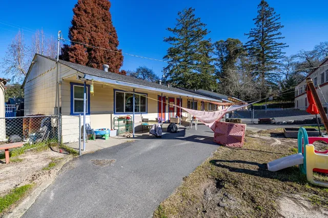 a view of a patio with table and chairs under an umbrella with large trees