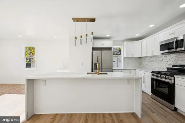 a kitchen with stainless steel appliances granite countertop a sink a stove top oven a counter space and cabinets