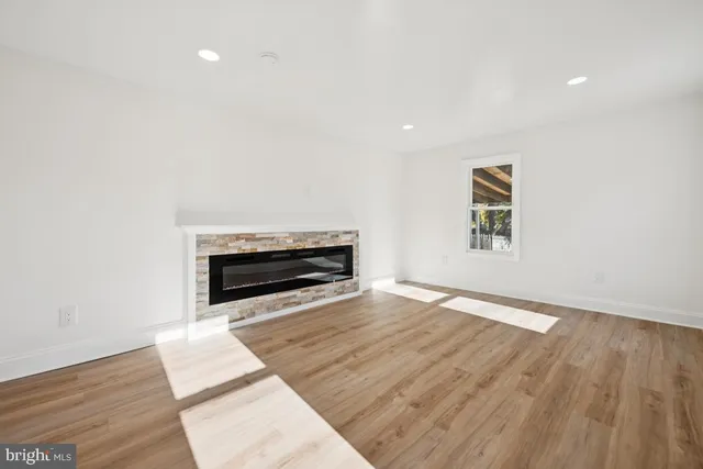 a view of empty room with wooden floor and fireplace