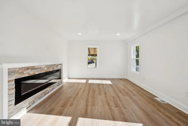 an empty room with wooden floor fireplace and window