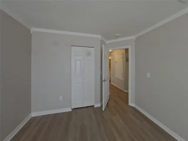 a view of an empty room with wooden floor and closet