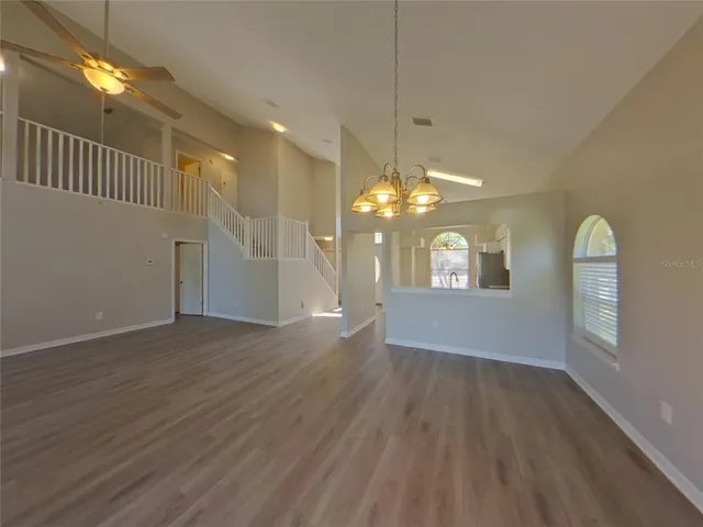 a view of a livingroom with a hardwood floor ceiling fan and kitchen space