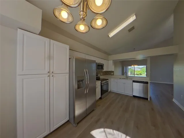 a kitchen with stainless steel appliances granite countertop a refrigerator a stove and a wooden floors