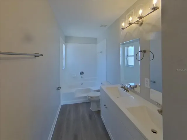 a bathroom with a bathtub shower sink vanity and toilet