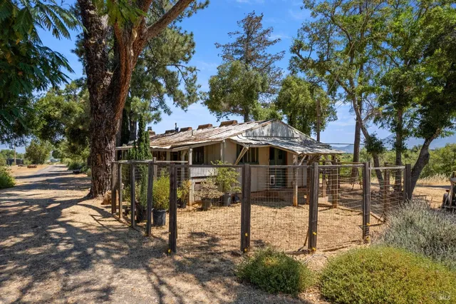 a view of a barn house next to a yard with large trees