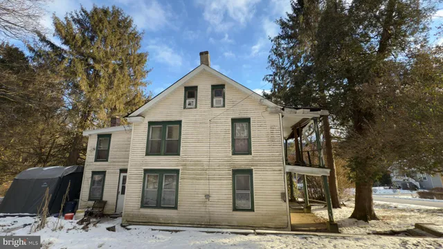 a view of a white house with large tree and wooden fence
