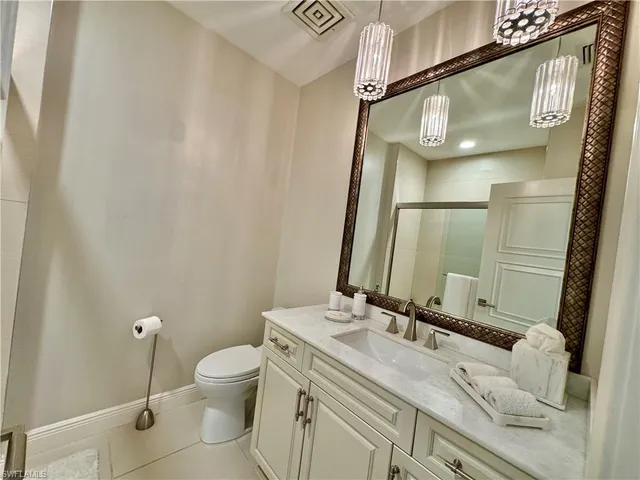 a bathroom with a granite countertop sink mirror vanity and toilet
