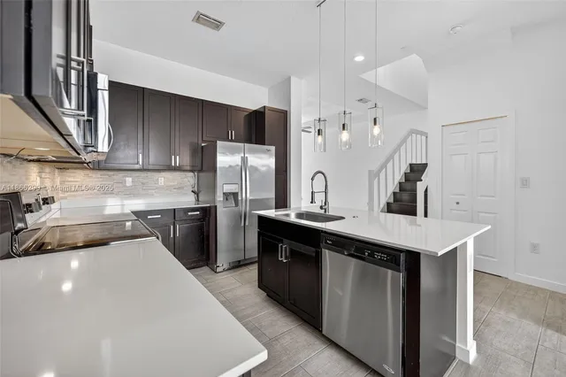 a kitchen with stainless steel appliances a sink and a refrigerator
