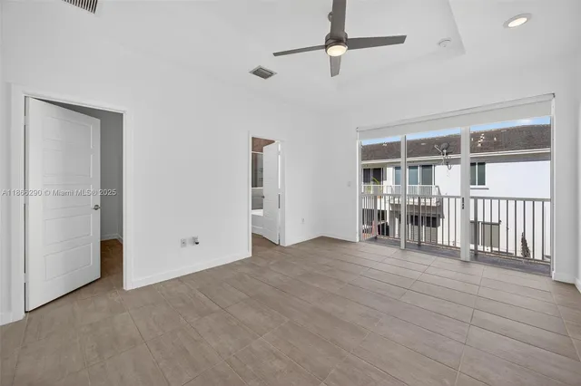 an empty room with windows and a ceiling fan
