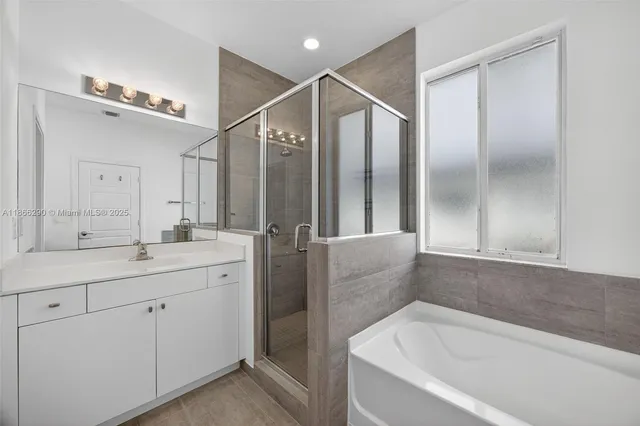 a bathroom with a bathtub a double vanity sink and mirror