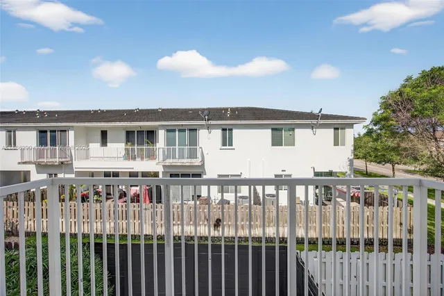 a view of a white house with a wooden floor and fence
