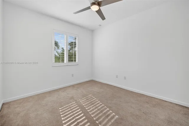 an empty room with a window and a fan