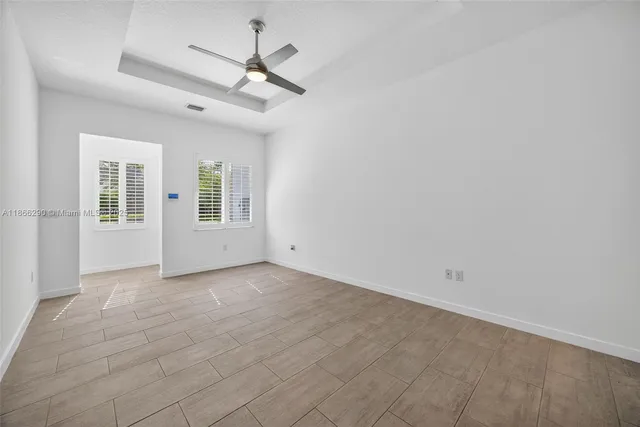 an empty room with chandelier fan and windows