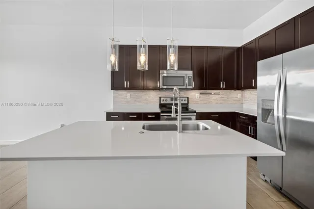a kitchen with kitchen island a sink stainless steel appliances and cabinets