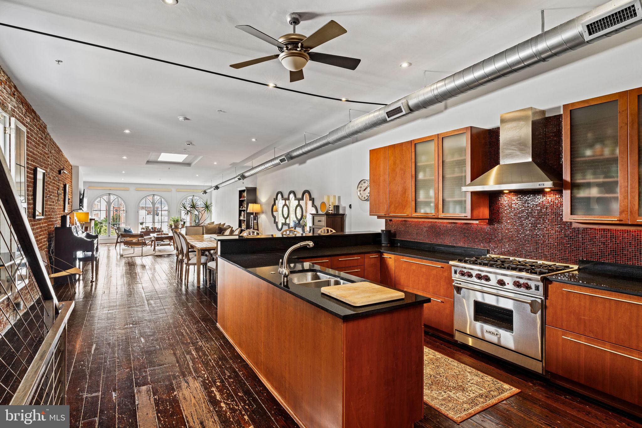 a kitchen with stainless steel appliances granite countertop a stove top oven a sink dishwasher a dining table and chairs with wooden floor