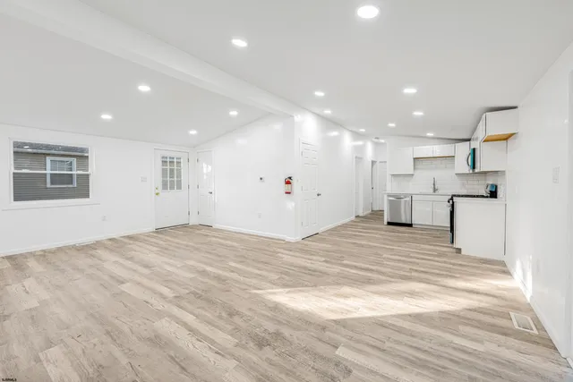 a view of a kitchen with kitchen island a sink wooden floor and a refrigerator