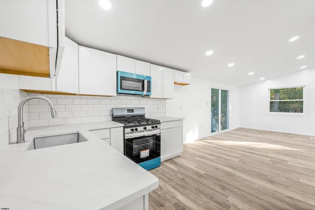 a kitchen with stainless steel appliances granite countertop a sink and a stove top oven with wooden floor